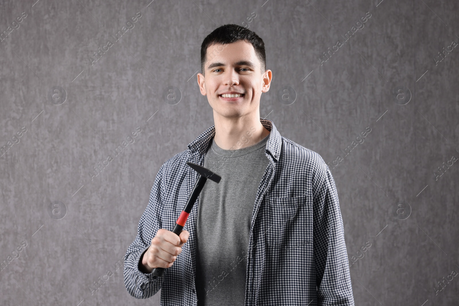 Photo of Young man holding hammer on grey background