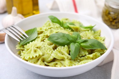 Delicious pasta with pesto sauce and basil on table, closeup