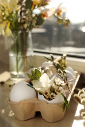 Festive composition with eggs and floral decor on windowsill indoors. Happy Easter