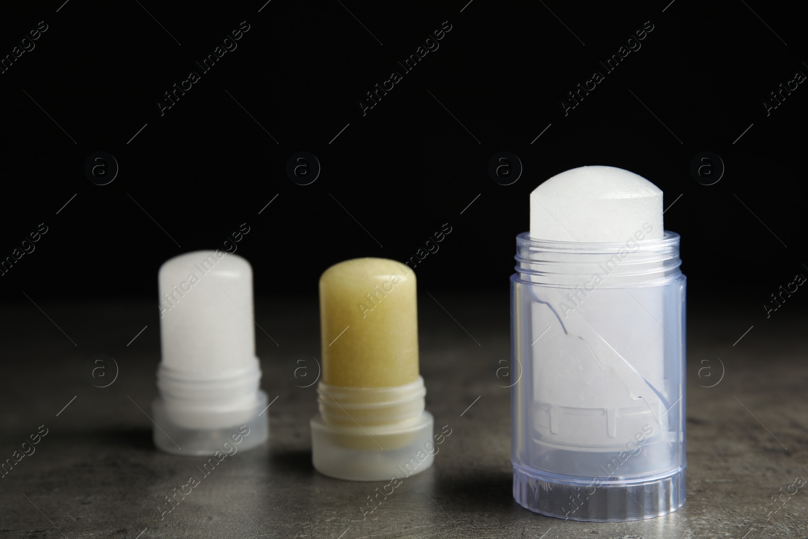 Photo of Natural crystal alum deodorants on grey table against black background