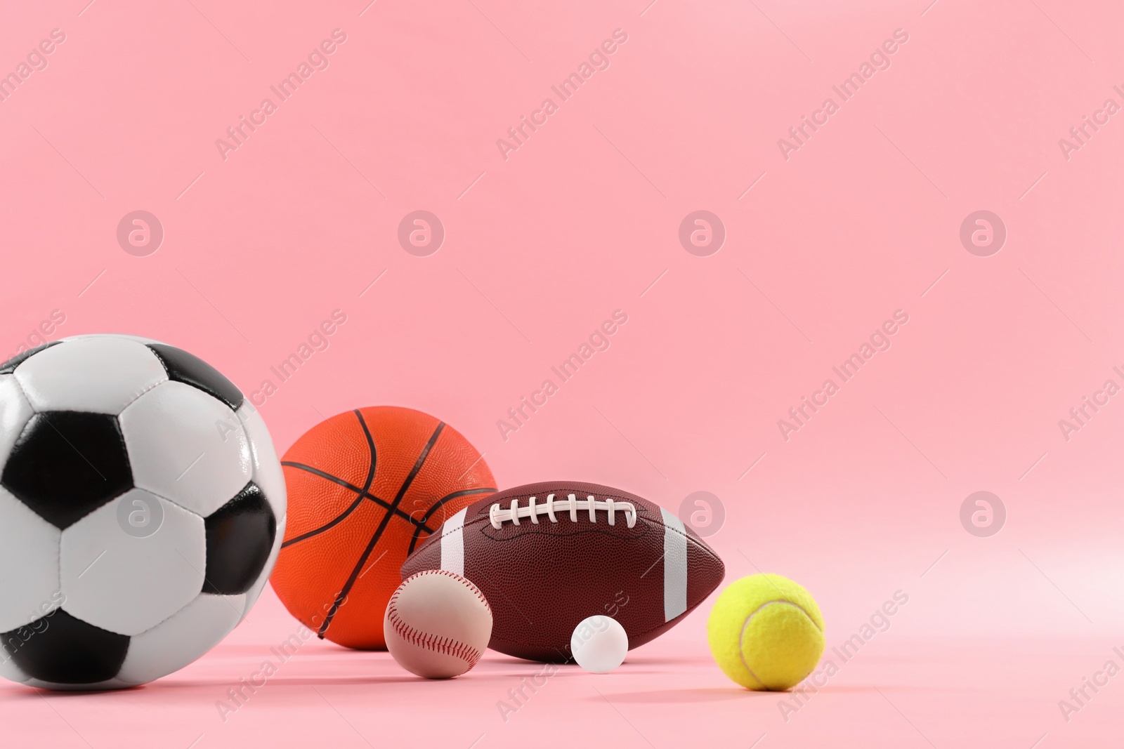 Photo of Many different sports balls on pink background, space for text