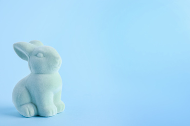 Easter bunny toy on light blue background. Space for text