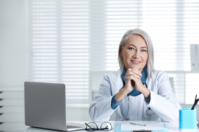 Photo of Portrait of mature female doctor in white coat at workplace