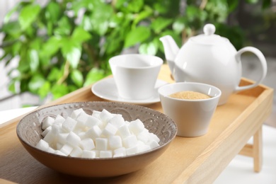 Bowl with refined sugar and tea on tray table