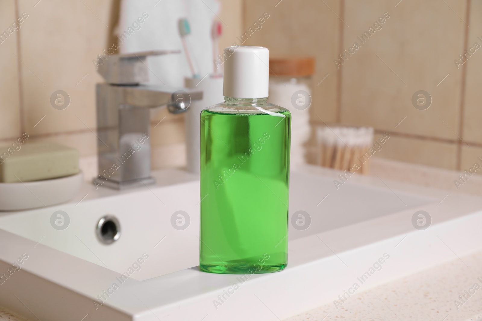 Photo of Fresh mouthwash in bottle on sink in bathroom, closeup