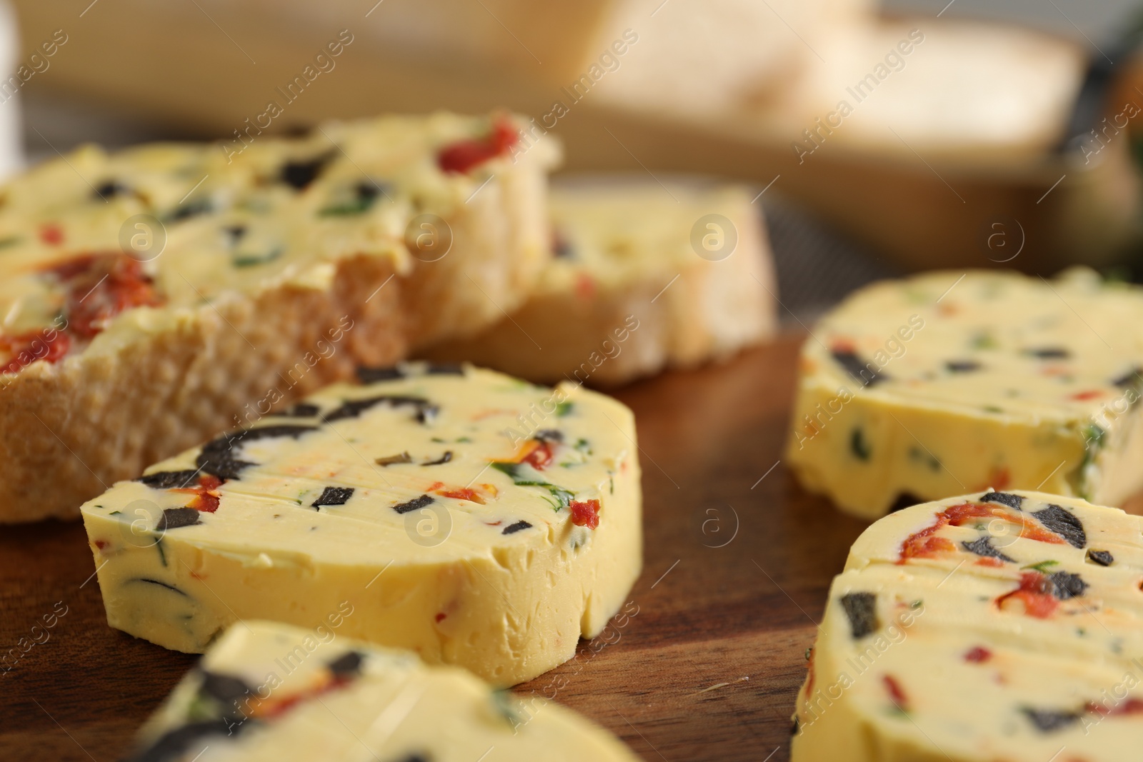 Photo of Tasty butter with olives, chili pepper and parsley on wooden table, closeup