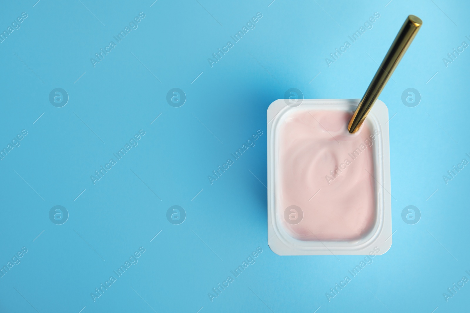 Photo of Tasty organic yogurt on light blue background, top view. Space for text