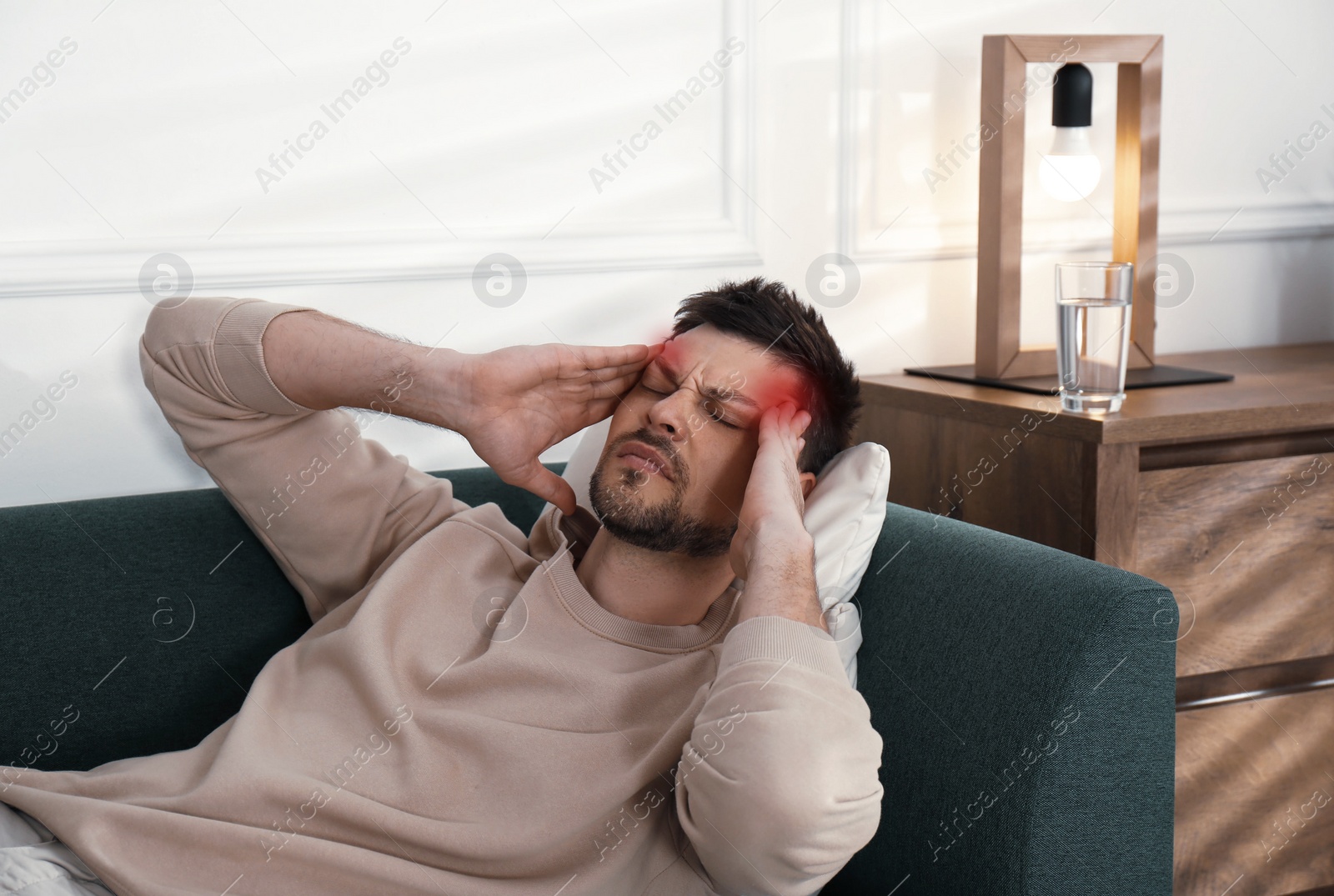Image of Man suffering from terrible migraine on sofa at home