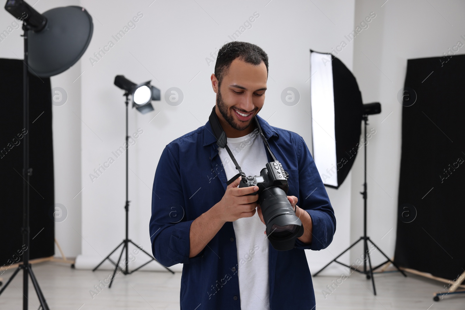 Photo of Young professional photographer with camera in modern photo studio