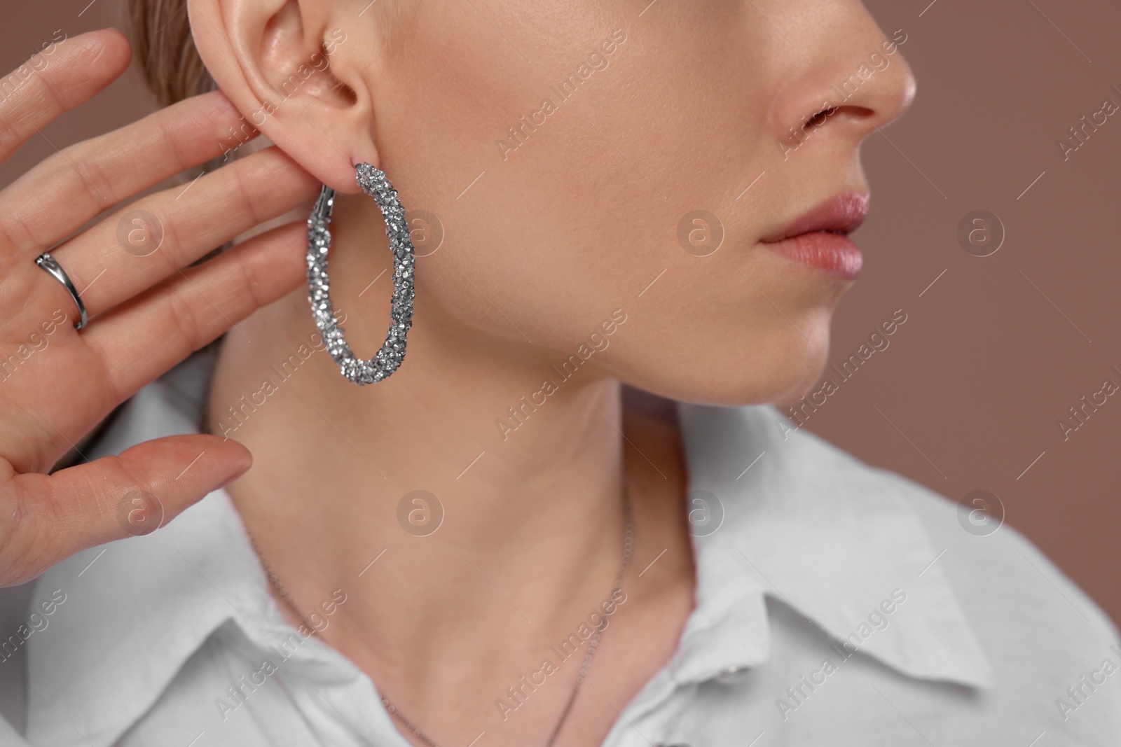 Photo of Woman with elegant jewelry on light brown background, closeup