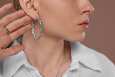 Woman with elegant jewelry on light brown background, closeup