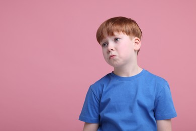 Photo of Portrait of sad little boy on pink background, space for text