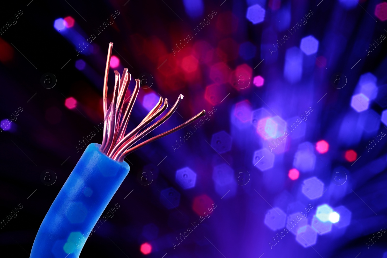 Image of One electrical wire against dark background with blurred lights, closeup. Space for text