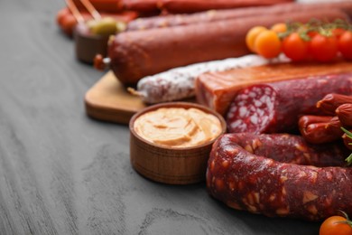 Different types of tasty sausages on grey wooden table, closeup. Space for text
