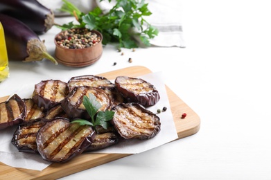 Photo of Delicious grilled eggplant slices with parsley and spices on white wooden table