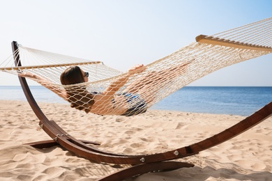 Photo of Young woman relaxing in hammock on beach