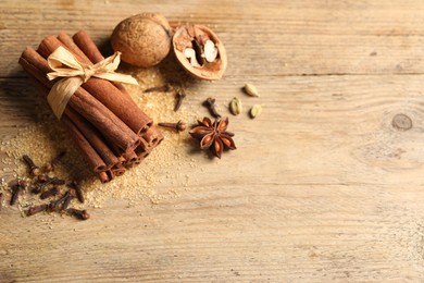 Photo of Different spices and nuts on wooden table, flat lay. Space for text