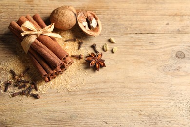 Different spices and nuts on wooden table, flat lay. Space for text