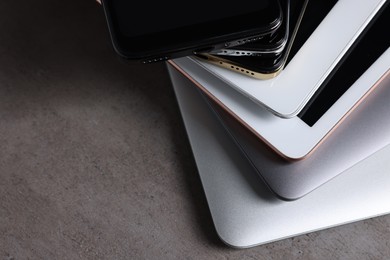 Photo of Many different modern gadgets on grey table, closeup. Space for text