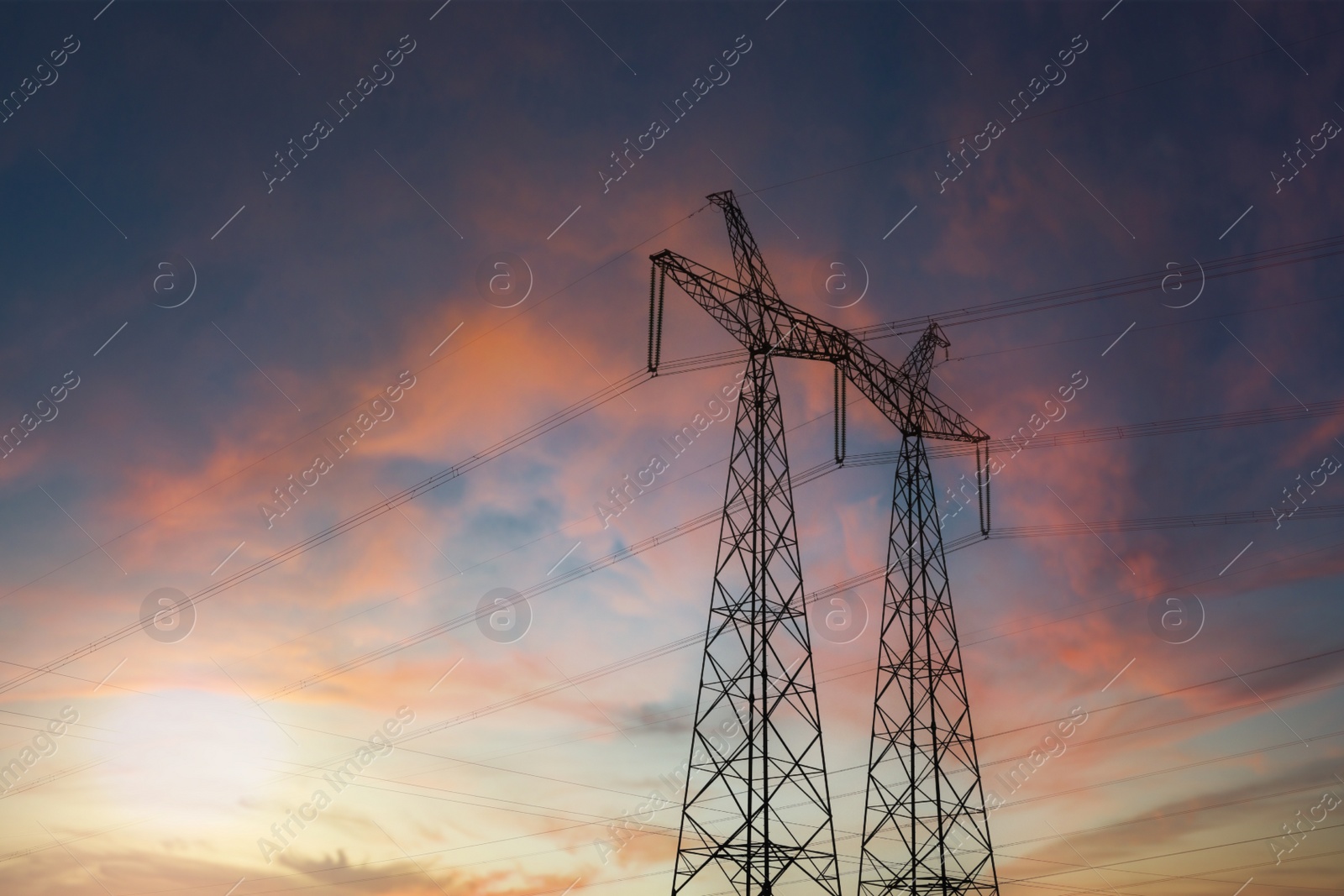 Photo of Telephone poles with cables at sunset outdoors