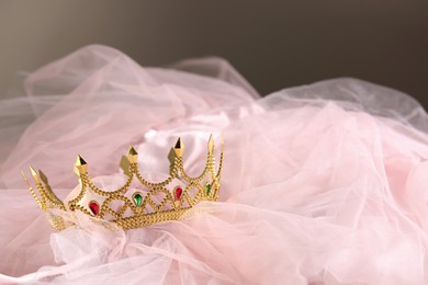 Photo of Beautiful gold tiara with gems on light cloth. Space for text