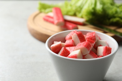 Photo of Cut crab sticks in bowl on light table, closeup. Space for text
