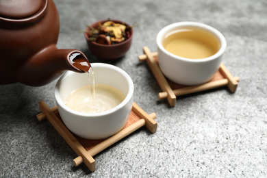 Photo of Pouring green tea into cup on grey table