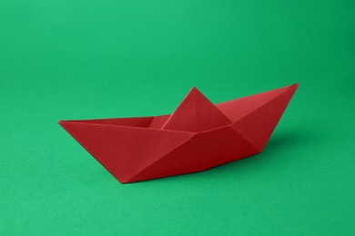 Origami art. Red paper boat on green background