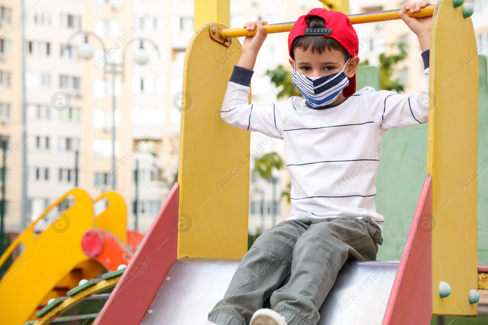 Photo of Little boy with medical face mask on playground during covid-19 quarantine