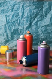 Photo of Cans of different graffiti spray paints on color background