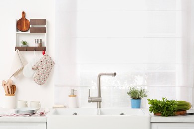 Photo of Kitchen counter with sinks, utensils and vegetables