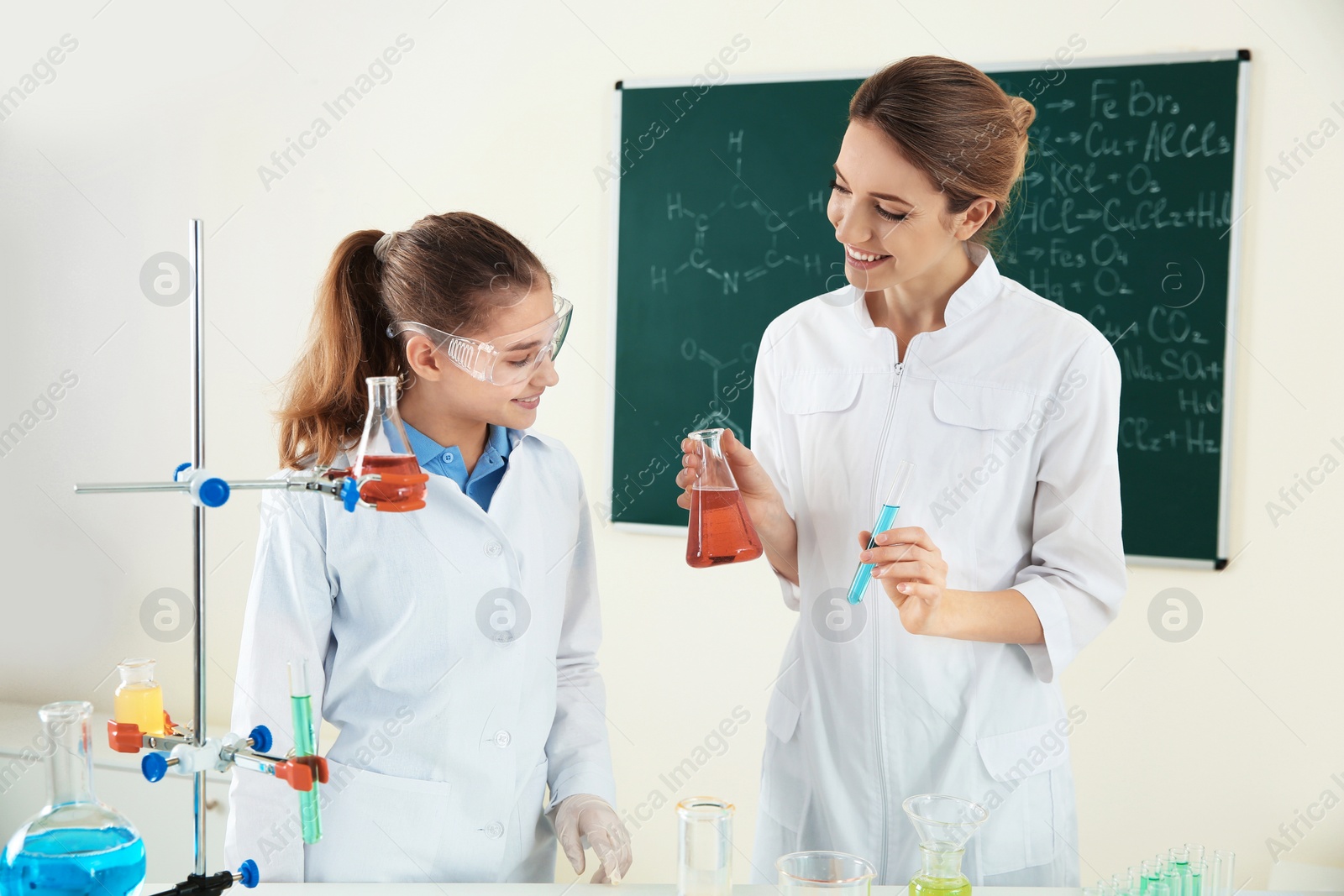 Photo of Teacher with pupil making experiment in chemistry class