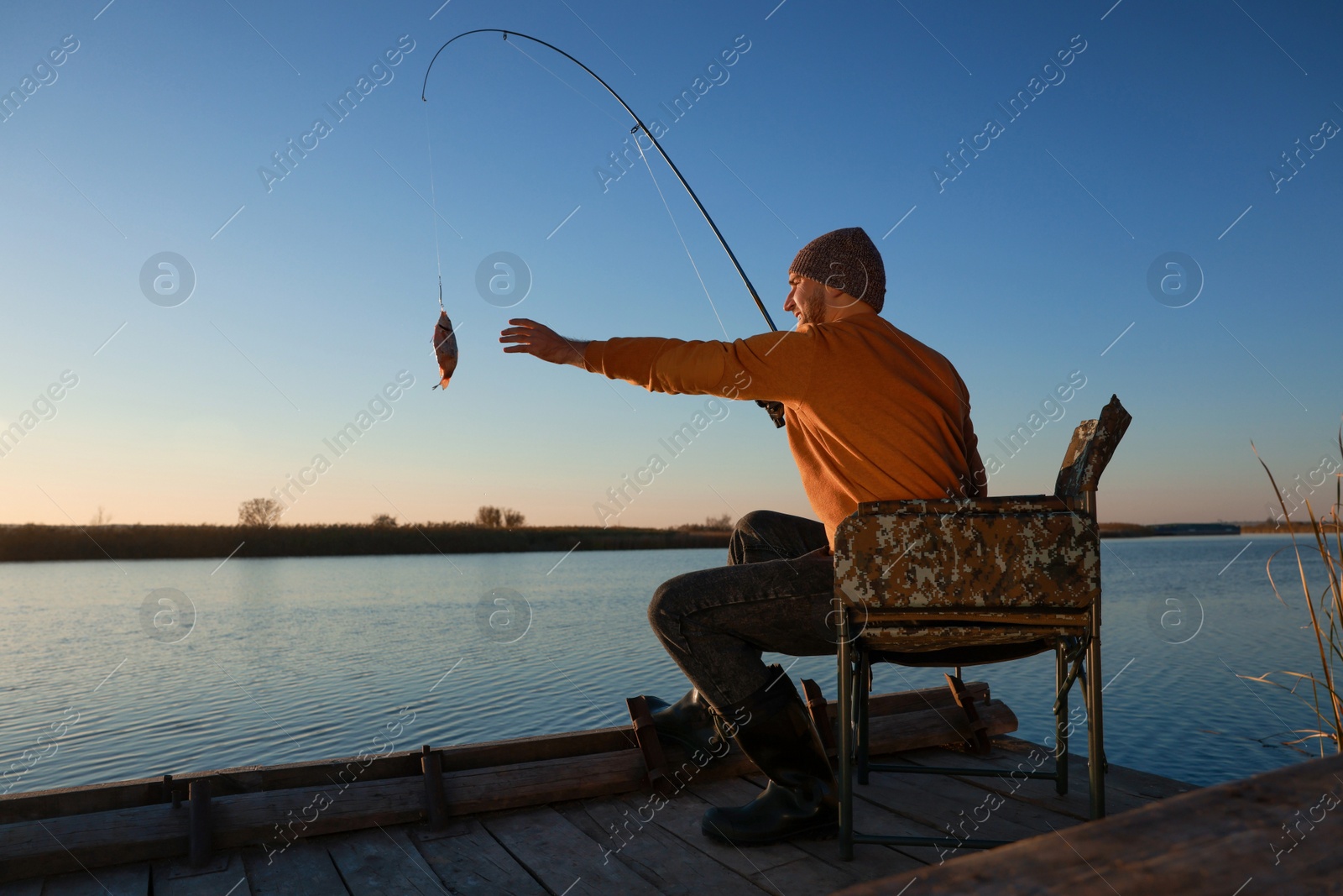 Photo of Fisherman catching fish with rod at riverside