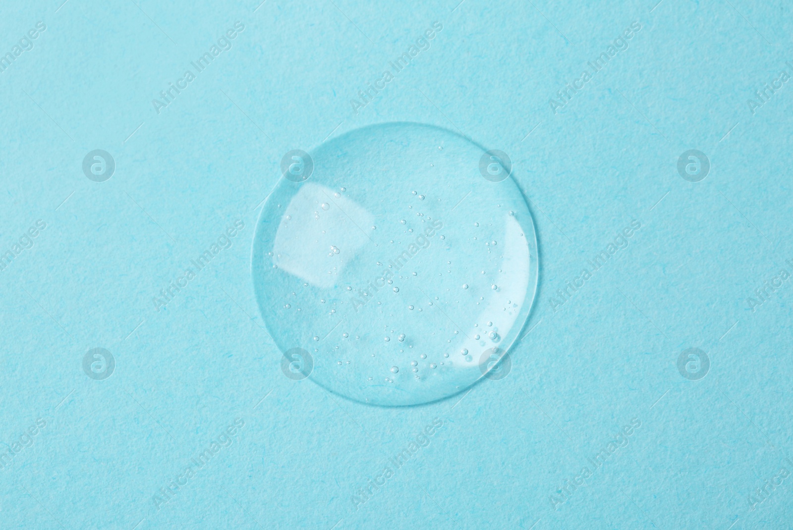 Photo of Sample of cosmetic serum on light blue background, top view