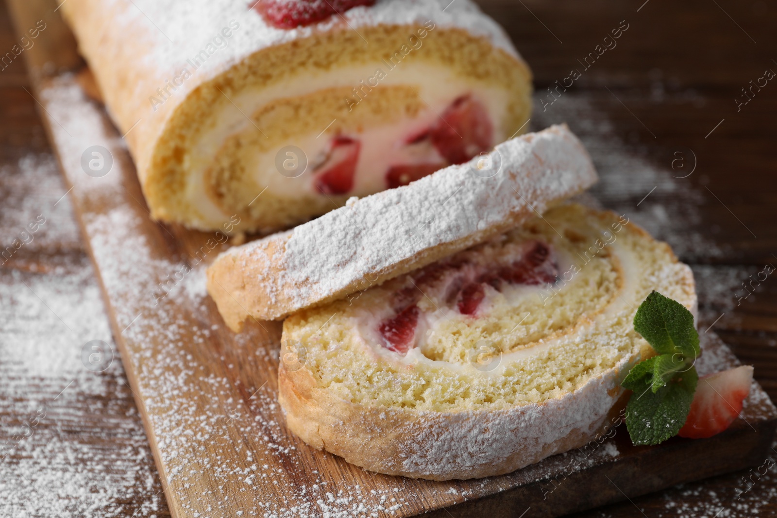 Photo of Pieces of delicious cake roll with strawberries and cream on table, closeup