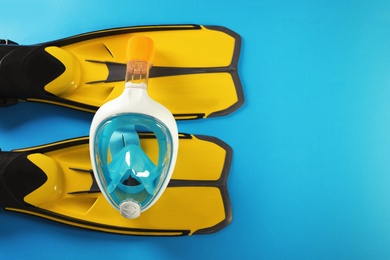 Pair of yellow flippers and diving mask on color background, top view with space for text