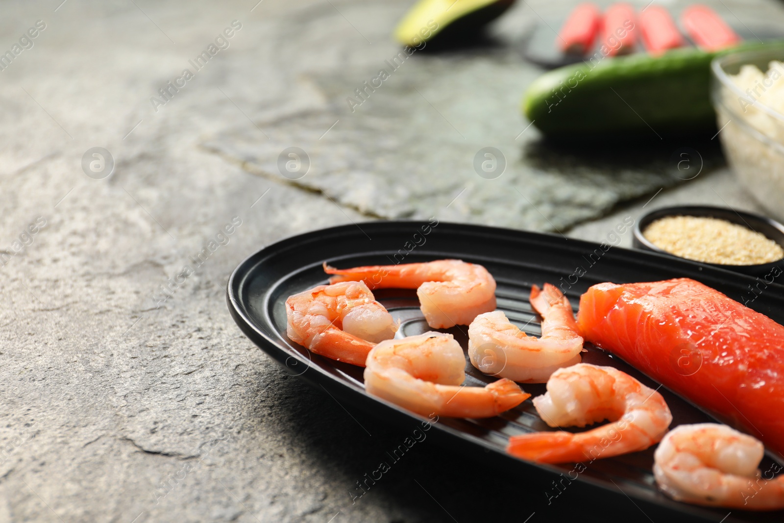 Photo of Fresh salmon, shrimps and other ingredients for sushi on dark textured table, closeup. Space for text