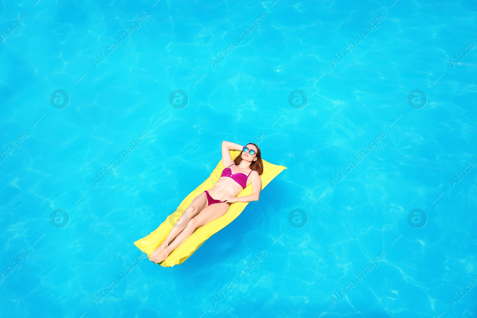 Photo of Young woman on inflatable mattress in swimming pool, above view