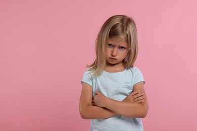 Photo of Resentment. Upset little girl with crossed arms on pink background. Space for text