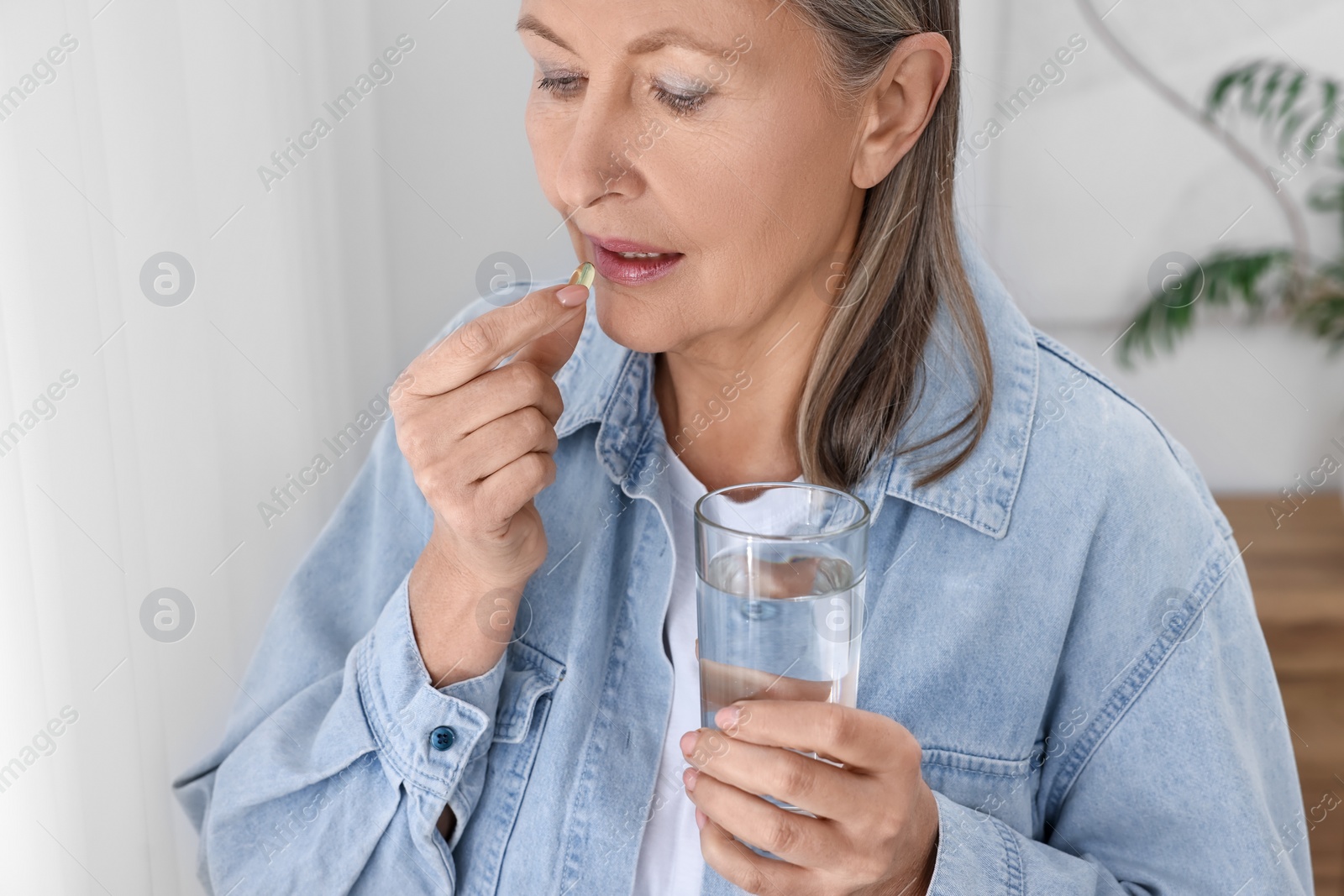 Photo of Beautiful woman taking vitamin pill at home