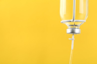 Photo of IV infusion set on yellow background, closeup. Space for text