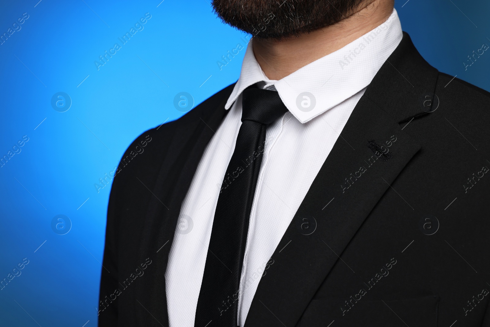 Photo of Businessman in suit and necktie on blue background, closeup