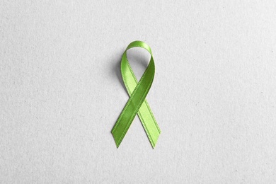 Green ribbon on color background, top view. Cancer awareness