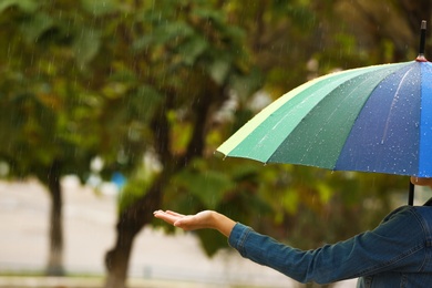 Photo of Woman with bright umbrella under rain on street, closeup