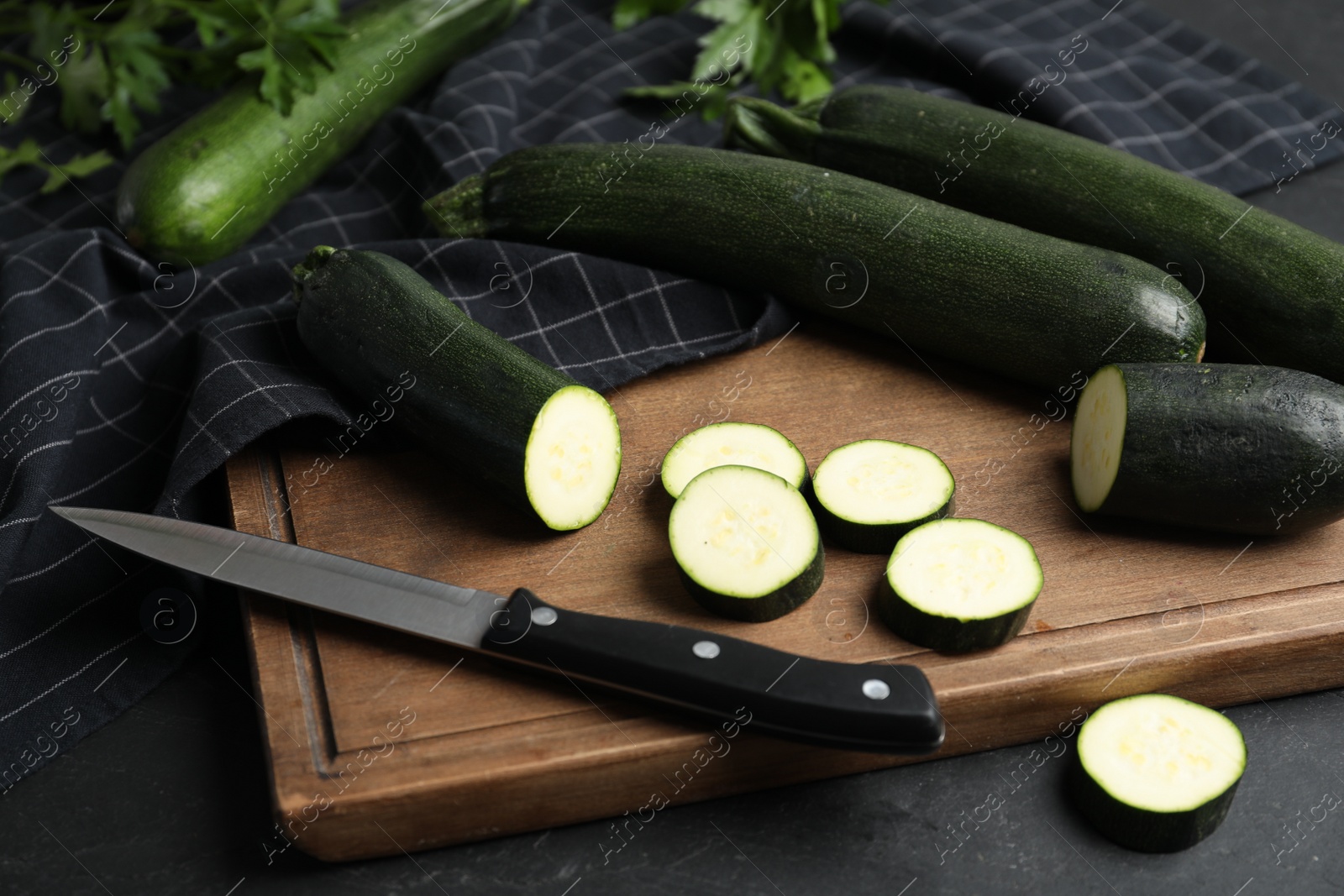 Photo of Green ripe zucchinis and wooden board on black slate table