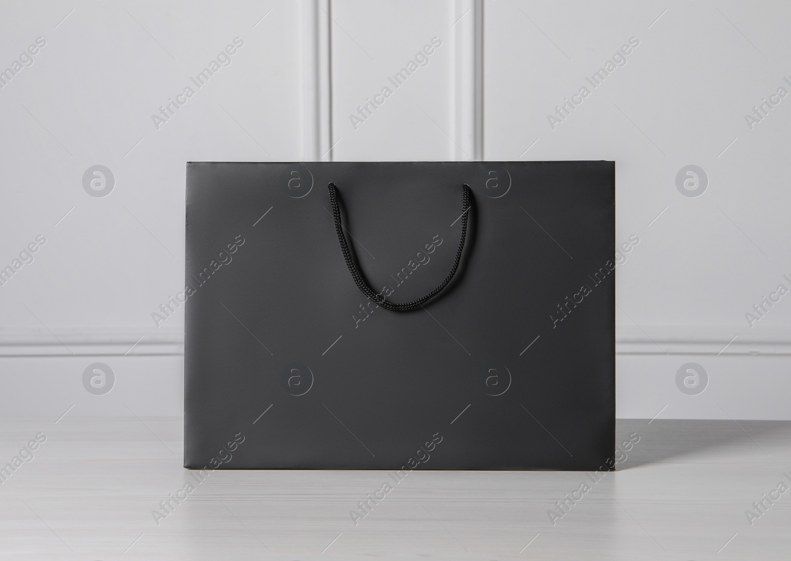 Photo of Black paper bag on white wooden table