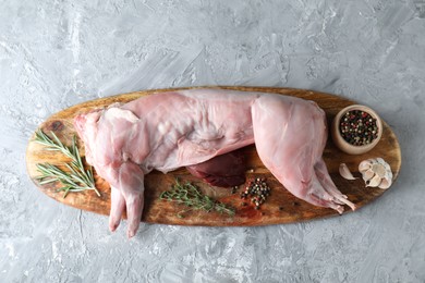 Photo of Whole raw rabbit, liver and spices on grey textured table, top view