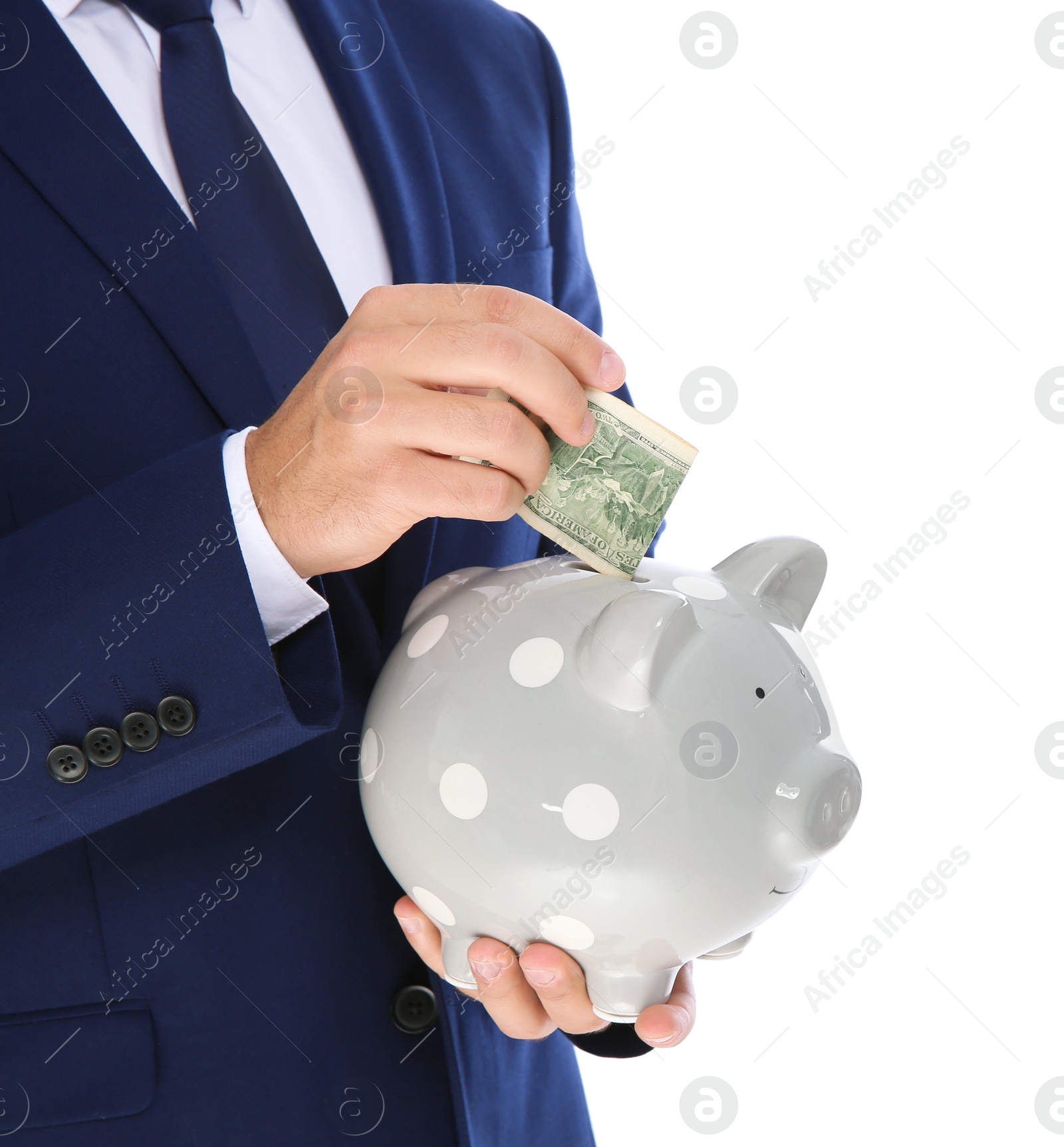Photo of Young businessman putting money into piggy bank on white background, closeup