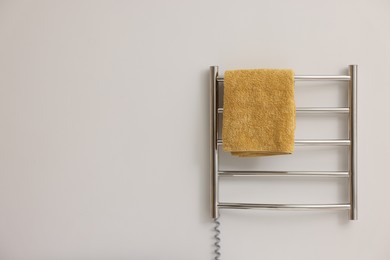 Photo of Heated rail with yellow towel on white wall, space for text