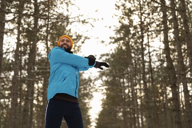 Photo of Man doing sports exercises in winter forest, low angle view